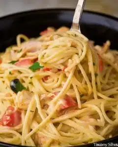 Close-up of CrockPot Cheesy Chicken Spaghetti with creamy cheese sauce, shredded chicken, and spaghetti noodles on a fork