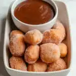 Irresistible Air Fryer Churro Bites – Sweet, Golden & So Easy! 9 Golden churro bites coated in cinnamon sugar, served with a bowl of chocolate sauce in a ceramic tray