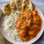 Creamy homemade butter chicken served with white rice and naan bread on a ceramic plate