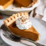 Pumpkin Pie Recipe: Silky, Spiced, and Holiday-Ready 9 Silky slice of pumpkin pie with whipped cream and flaky crust on a white plate with cinnamon dusting