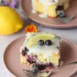Lemon Blueberry Sheet Cake That Tastes Like Summer 12 Close-up of lemon blueberry sheet cake with lemon glaze and fresh blueberry garnish on a plate