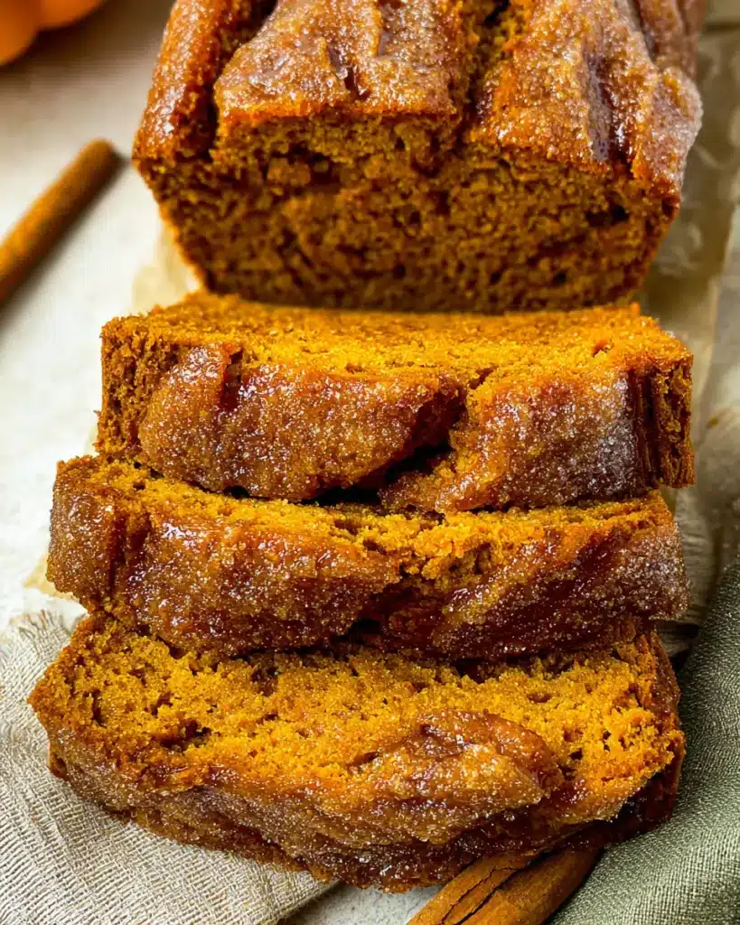 Perfect Pumpkin Bread That's Moist with a Crunchy Sugar Crust 8 Sliced pumpkin bread loaf with sugar crust on parchment paper