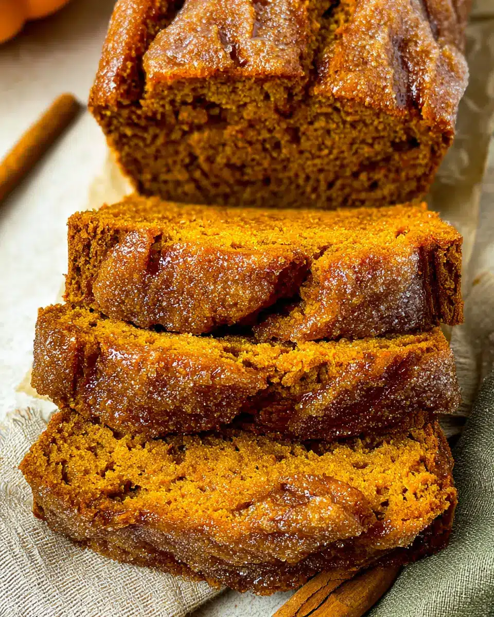 Sliced pumpkin bread loaf with sugar crust on parchment paper