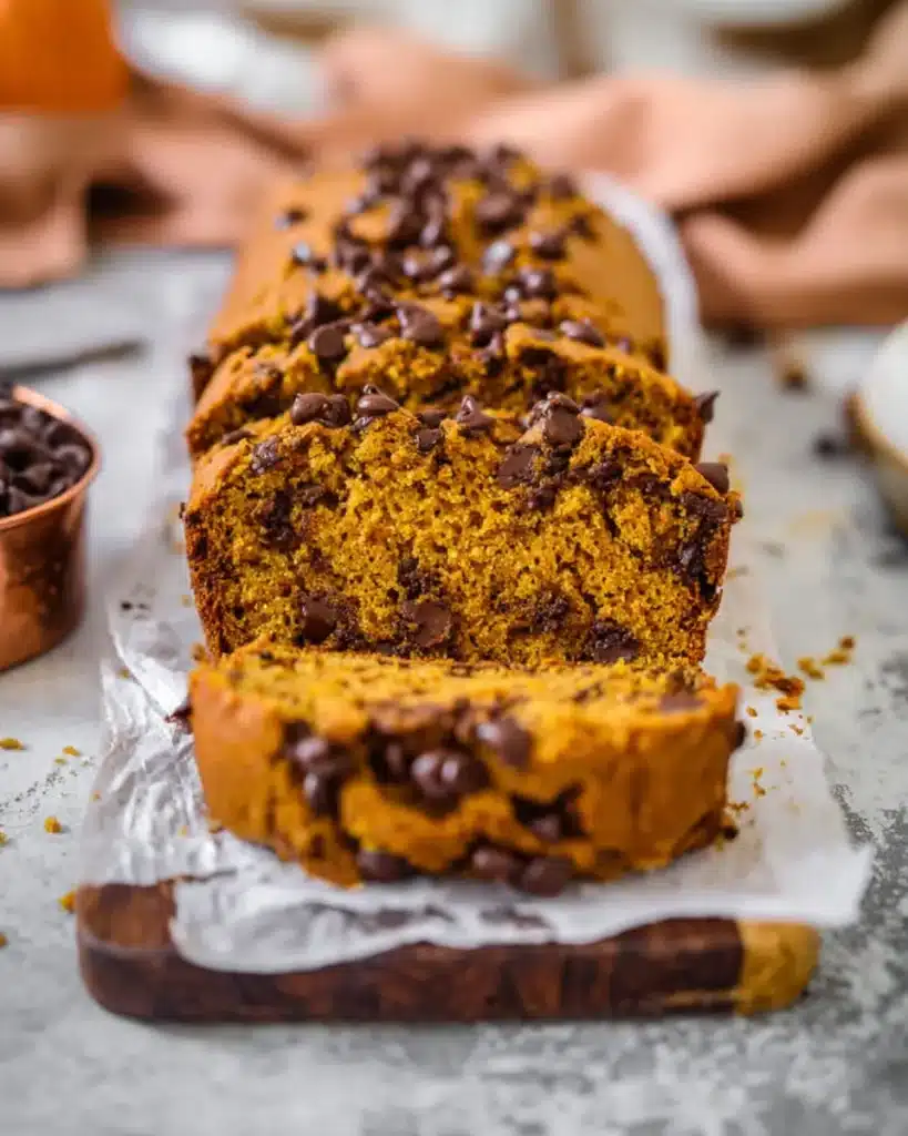 Sliced loaf of moist pumpkin chocolate chip bread with crisp crust and melty chips

