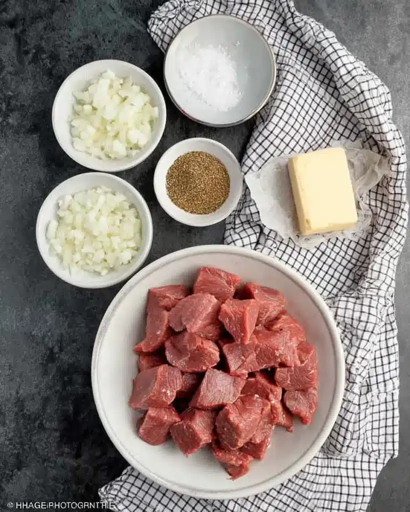 Crockpot Steak Bites – Easy, Tender, and Bursting with Flavor 7 Overhead shot of raw ingredients for crockpot steak bites including beef cubes, garlic, onions, and butter