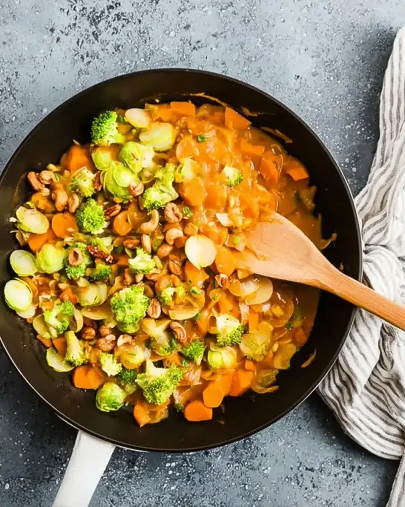 Thai Pumpkin Curry That’s Creamy, Cozy, and Easy to Make 8 Thai pumpkin curry served in a skillet with broccoli and cashews, styled for fall with pumpkins, cilantro, and lime