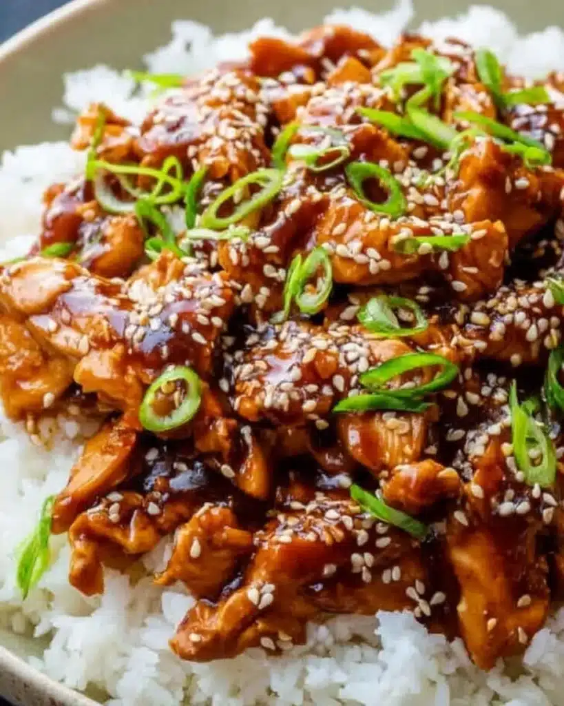 20+ Easy Crockpot Meals for Summer That Won’t Heat Up Your Kitchen 11 Slow-cooked teriyaki chicken with sesame seeds and scallions over rice on a ceramic plate