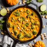 Thai Pumpkin Curry That’s Creamy, Cozy, and Easy to Make 9 Colorful Thai pumpkin curry in a cast iron skillet with broccoli, cashews, and fall garnishes on a rustic table