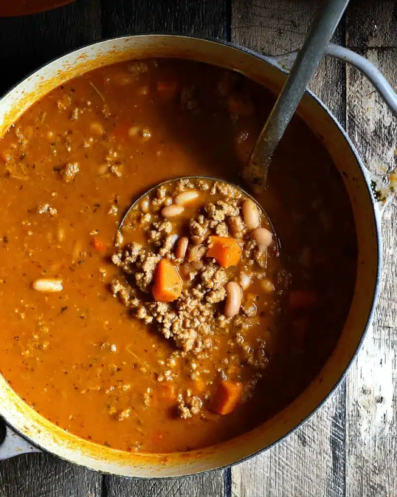 Chicken Chili with Pumpkin (Ultimate One-Pot Comfort Recipe) 7 Pot of simmering chicken chili with pumpkin, beans, and spices being stirred with a ladle