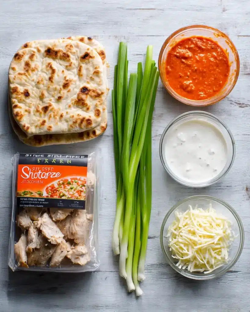 Buffalo chicken flatbread ingredients including artisan flatbread, buffalo sauce, cooked chicken, blue cheese dressing, green onions, and shredded mozzarella.