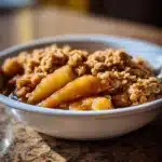Classic Apple Crisp Recipe for Cozy Comfort 11 A warm bowl of classic apple crisp with golden apples and a crunchy oat topping served in a white dish.