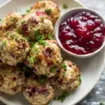 Cranberry Turkey Stuffing Balls – Festive and Flavorful Holiday Bites 11 Cranberry turkey stuffing balls with cranberry sauce on a plate