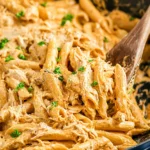 Creamy buffalo chicken pasta with penne, shredded chicken, and melted cheese in a skillet with parsley garnish