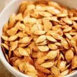Crispy Pumpkin Seeds – Easy Air Fryer Recipe 11 Golden roasted pumpkin seeds in a white bowl, crispy and lightly salted