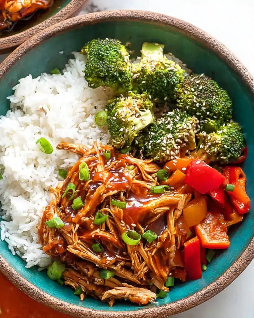 Top view of crock pot teriyaki chicken bowl with rice, broccoli, bell peppers, and sesame seeds.