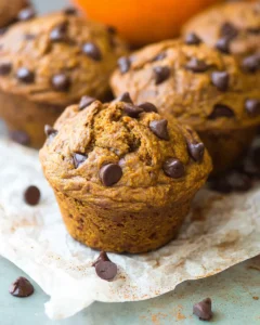 Moist pumpkin chocolate chip muffin topped with mini chocolate chips on parchment paper