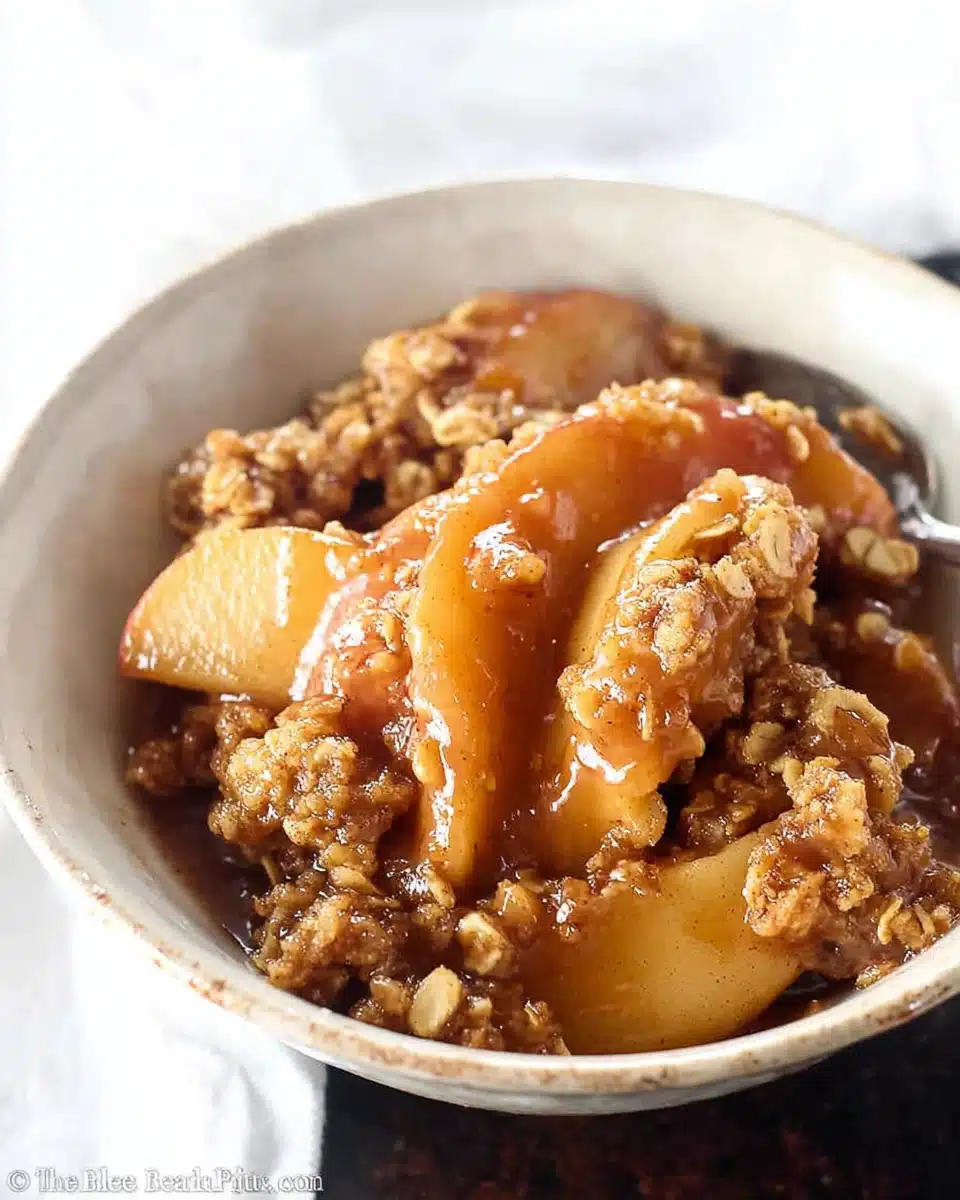 Warm apple crisp dessert with cinnamon-baked apples and golden oat topping in a white bowl