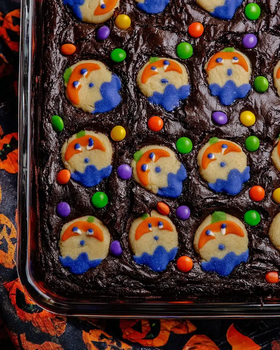Glass baking dish filled with Halloween brookies topped with ghost cookies and colorful M&M candies on a festive background.