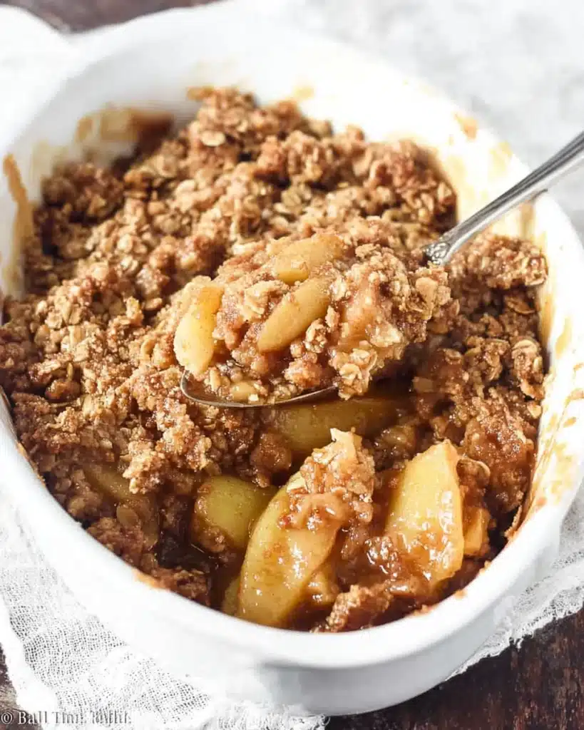 Freshly baked apple crisp with caramelized apples and golden oat crumble in a white dish