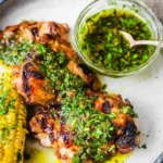 Grilled chimichurri chicken thighs served with fresh herb sauce and charred corn