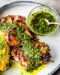 Grilled chimichurri chicken thighs served with fresh herb sauce and charred corn