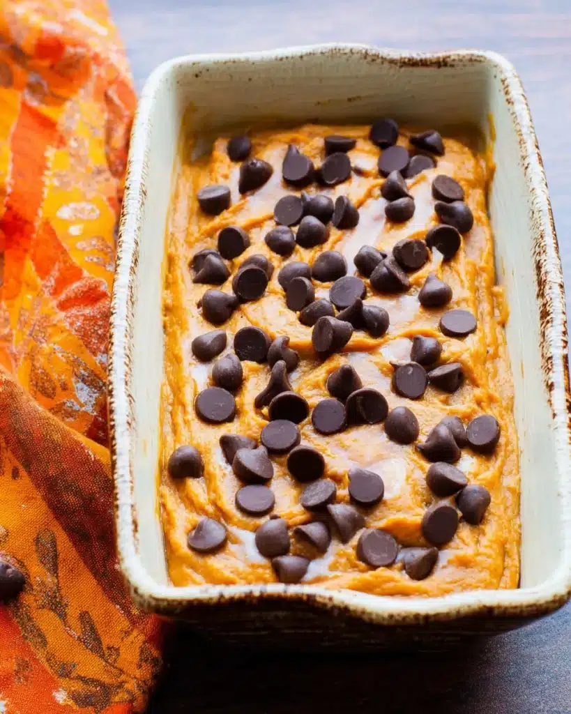 Pumpkin bread batter topped with chocolate chips in a loaf pan, ready to bake