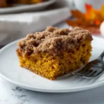 Pumpkin Coffee Cake – Soft, Spiced, and Perfect for Fall 14 A moist slice of pumpkin coffee cake with a cinnamon crumb topping on a white plate, perfect for fall.