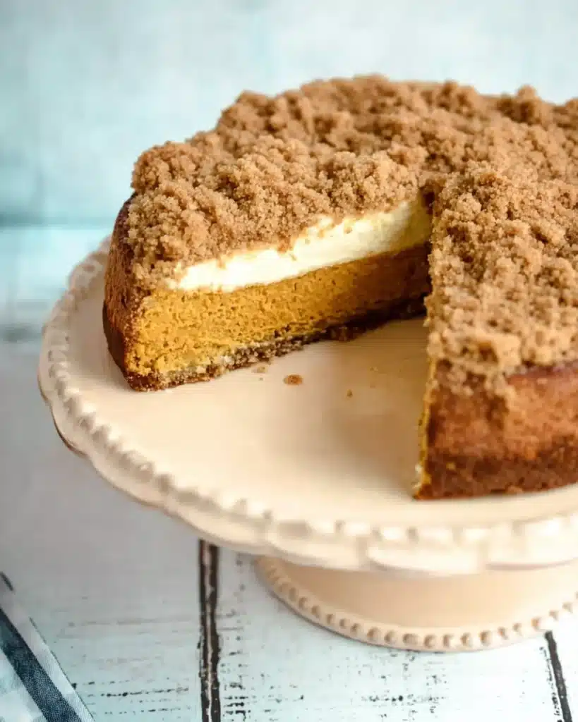 Pumpkin Cream Cheese Crumb Cake for Cozy Fall Baking 9 Whole pumpkin cream cheese crumb cake with streusel topping and one slice removed