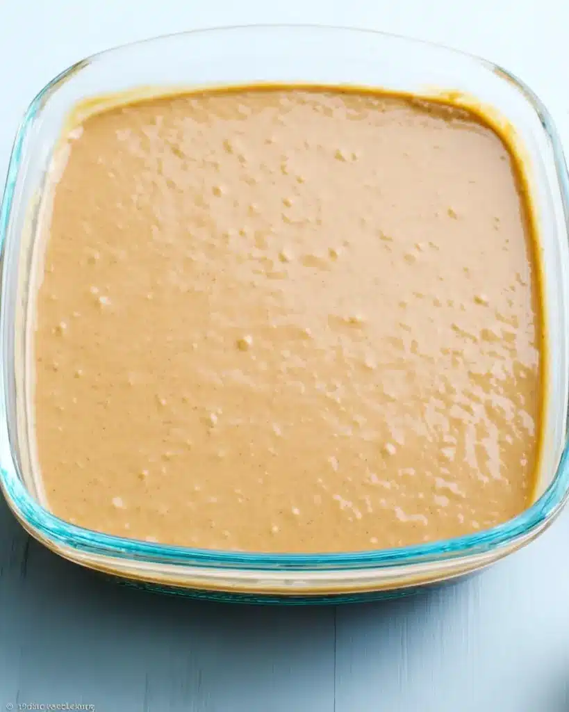 Pumpkin Magic Custard Cake – A Cozy Fall Dessert with Layers of Wonder 10 Unbaked pumpkin magic custard cake batter in a glass dish ready for the oven