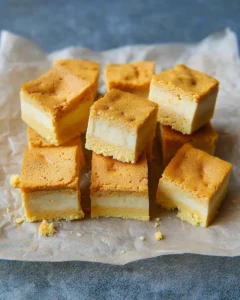 Close-up of sliced pumpkin magic custard cake with visible three-layer texture on a rustic background