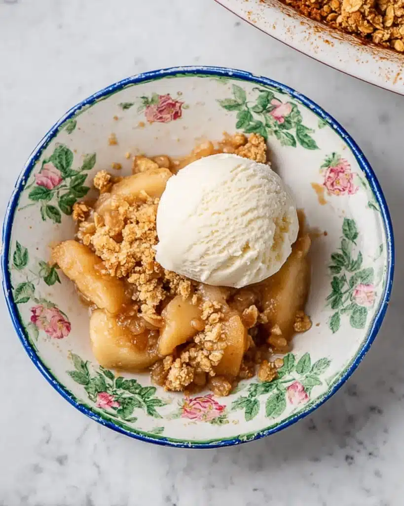Simple Apple Crumble – Cozy Dessert for Any Occasion 16 Apple crumble served with vanilla ice cream on a floral plate