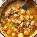 Hearty slow cooker chicken stew with potatoes and carrots in a rustic enameled pot