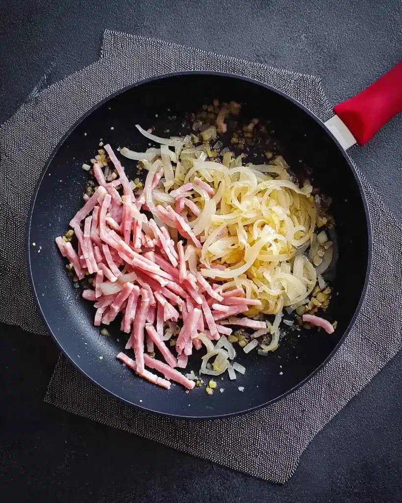 Spooky Pasta for Halloween with Creamy Bacon Sauce 12 Onions and bacon cooking in skillet for spooky pasta for Halloween