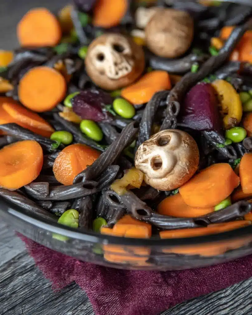Delicious Halloween Pasta Salad with Spooky Mushroom Skulls 13 Close-up of Halloween pasta salad with mushroom skulls, black noodles, and vegetables
