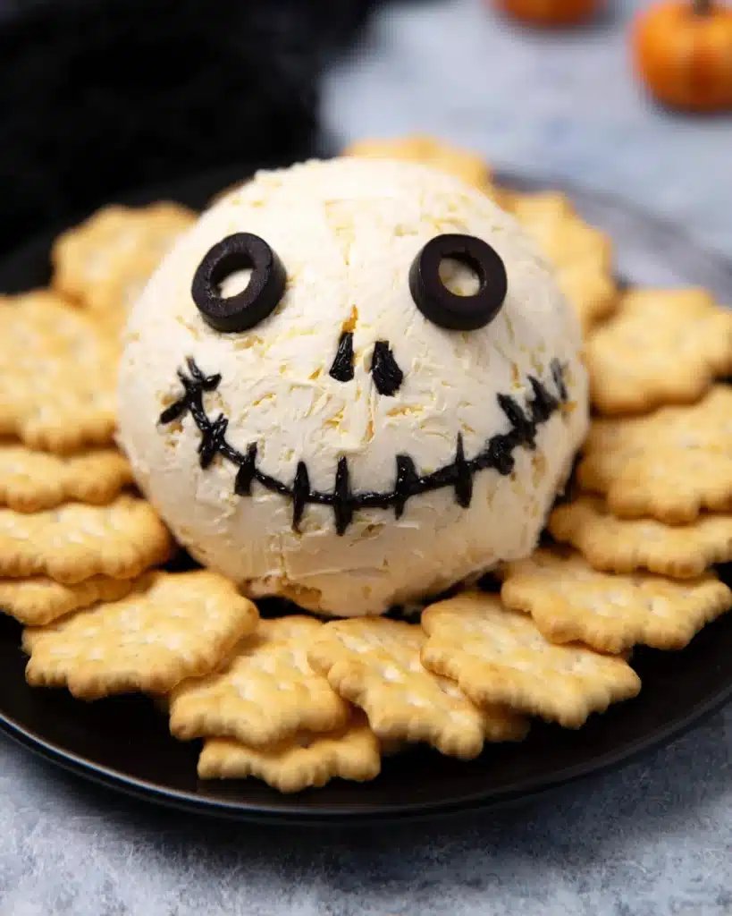 Skellington Cheese Ball Recipe | A Spooky Halloween Appetizer 12 Skellington cheese ball decorated with olives and served with golden crackers