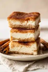 Churro cheesecake bars stacked with cinnamon sugar layers and creamy filling