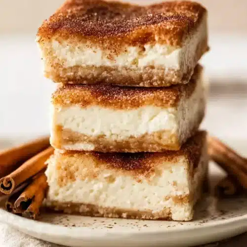 Churro cheesecake bars stacked with cinnamon sugar layers and creamy filling
