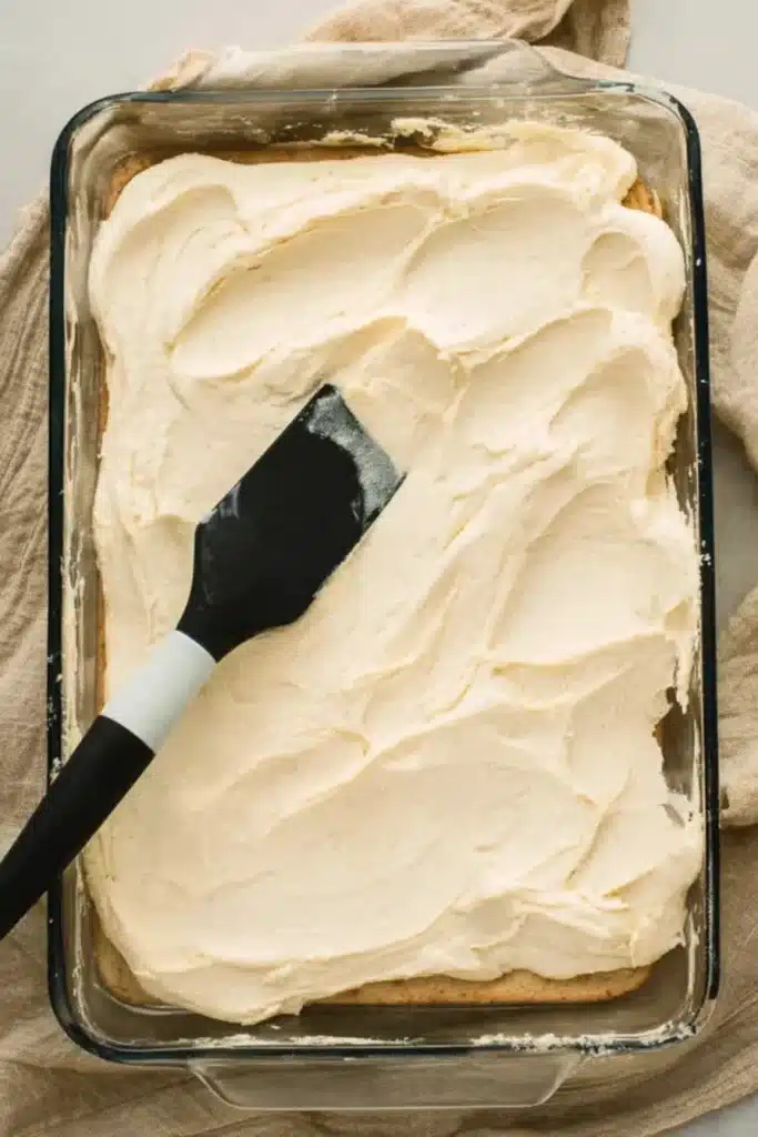 Spreading cream cheese filling for churro cheesecake bars in baking dish
