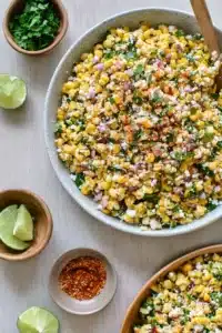 Elote corn salad with cheese, lime, and herbs in a bowl on a bright surface