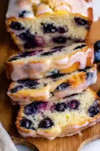 Moist lemon blueberry bread slices with glaze and fresh blueberries