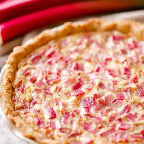 Rhubarb custard pie with creamy filling and golden crust on a rustic table