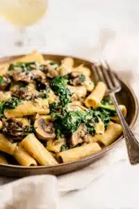 Creamy spinach mushroom pasta with rigatoni, sautéed mushrooms, and fresh spinach in a rich sauce