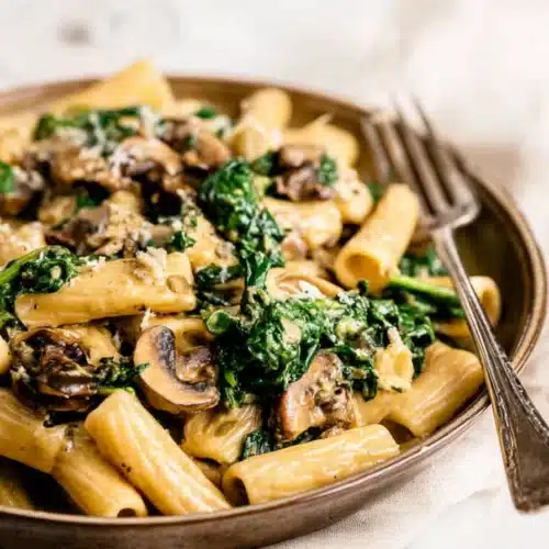 Creamy spinach mushroom pasta with rigatoni, sautéed mushrooms, and fresh spinach in a rich sauce