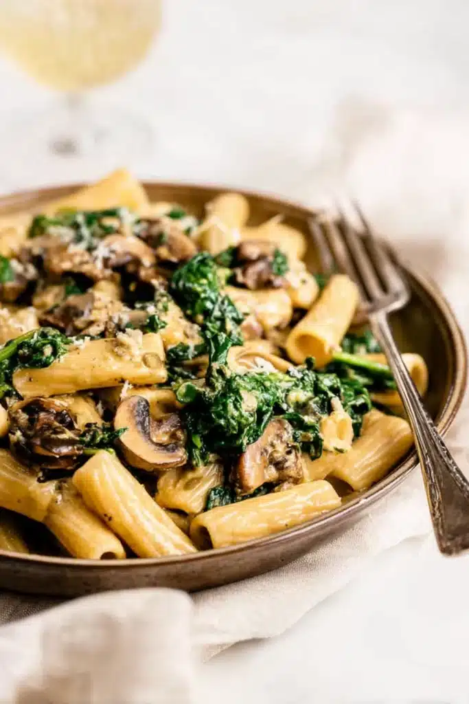 Creamy spinach mushroom pasta with rigatoni, sautéed mushrooms, and fresh spinach in a rich sauce