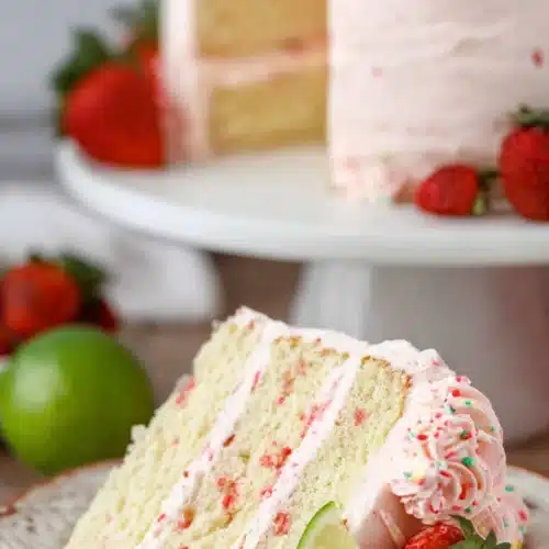 Strawberry margarita layer cake slice with lime and fresh strawberries on a plate