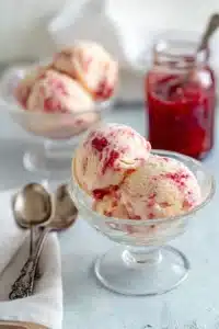 Rhubarb ice cream scoops with red fruit swirl in bowls