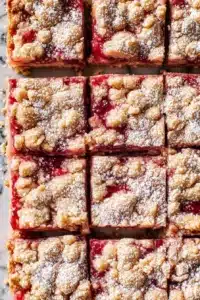 Gluten Free Rhubarb Crumble Bars with golden crumble topping and red filling
