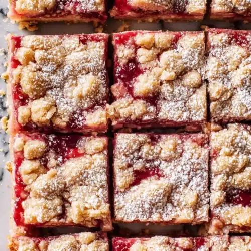 Gluten Free Rhubarb Crumble Bars with golden crumble topping and red filling