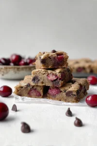 Cherry chocolate chip blondies stacked with fresh cherries and dark chocolate chips