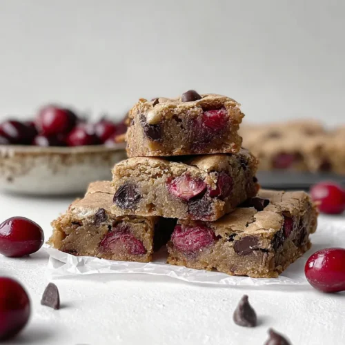 Cherry chocolate chip blondies stacked with fresh cherries and dark chocolate chips